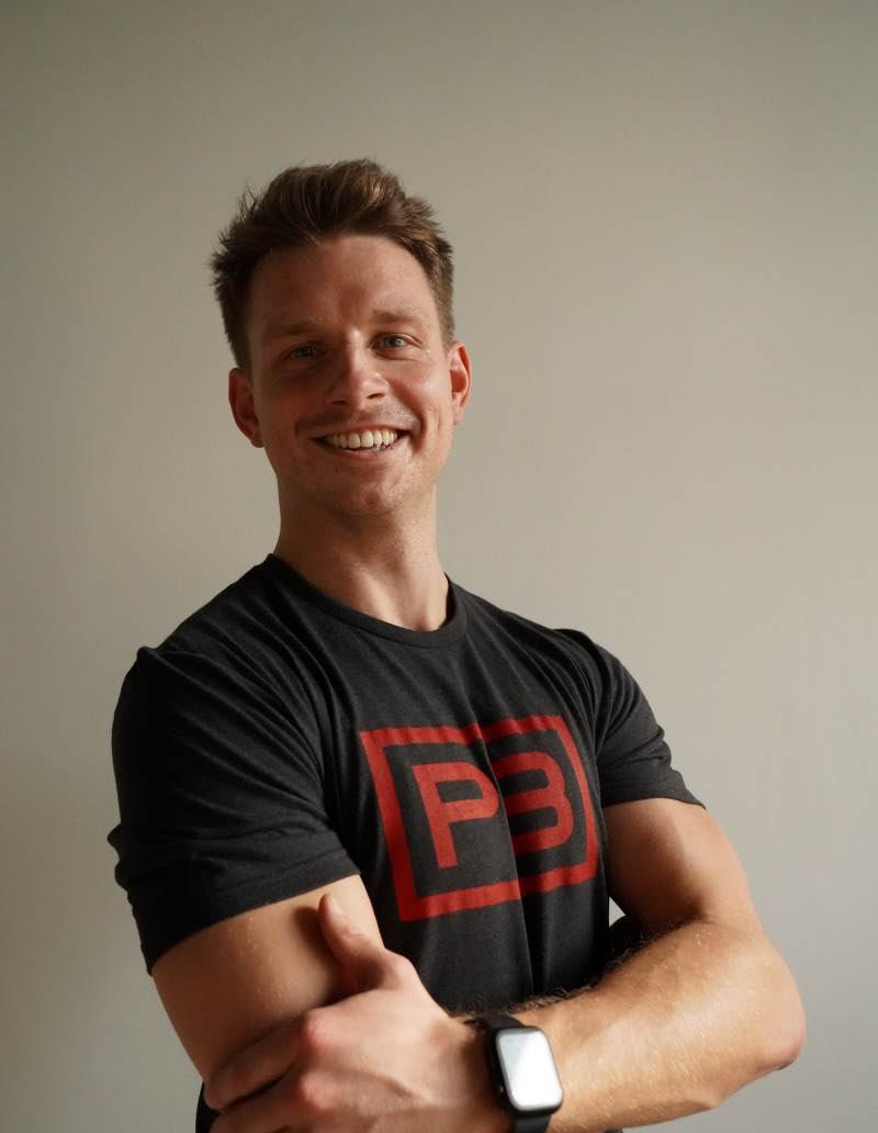 PowerBlock Fitness Studio's Coach Andy Wiedenkeller, posing for a headshot wearing a black powerblock shirt.