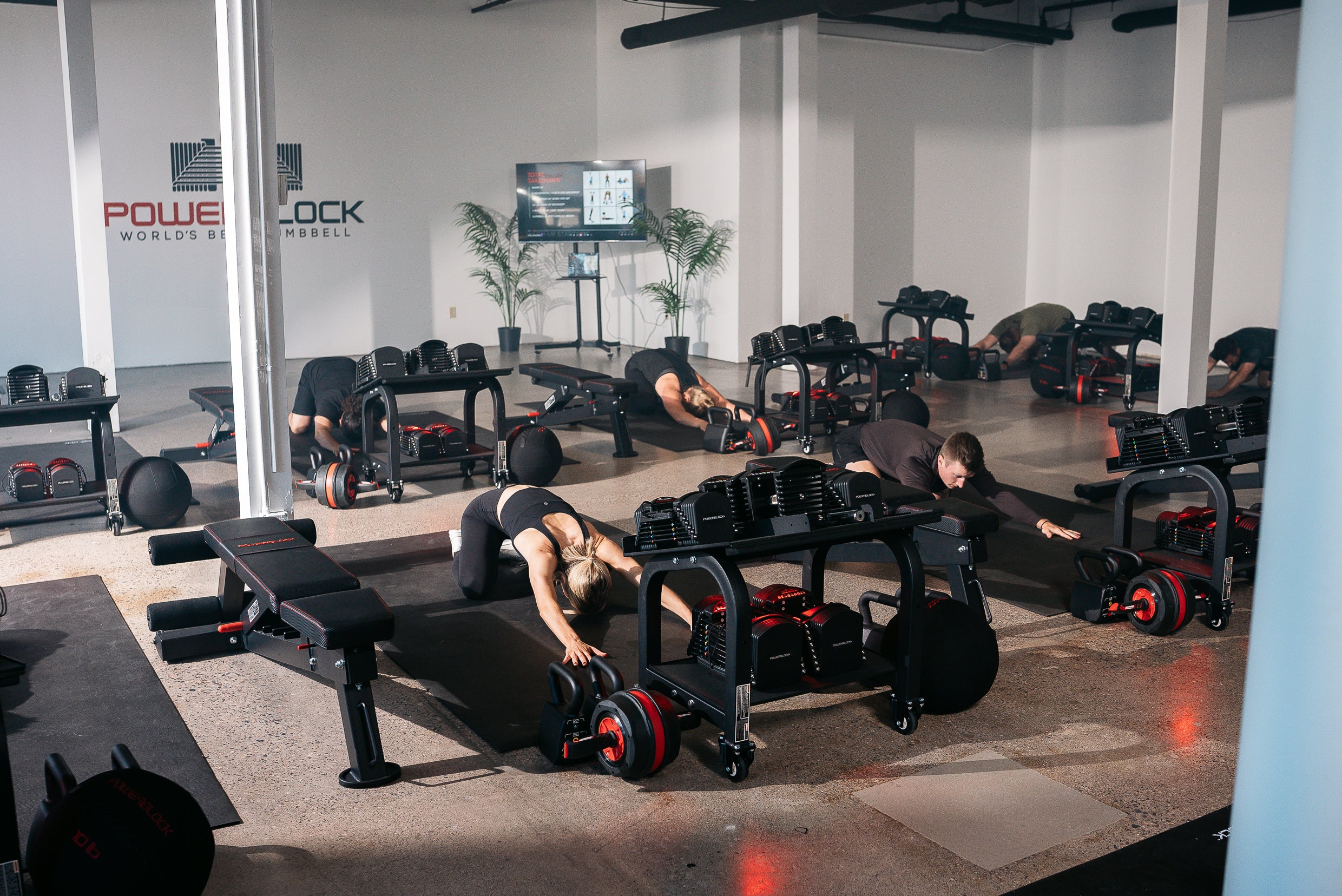 A powerblock fitness studio class, members can be seen stretching in the downward dog position.