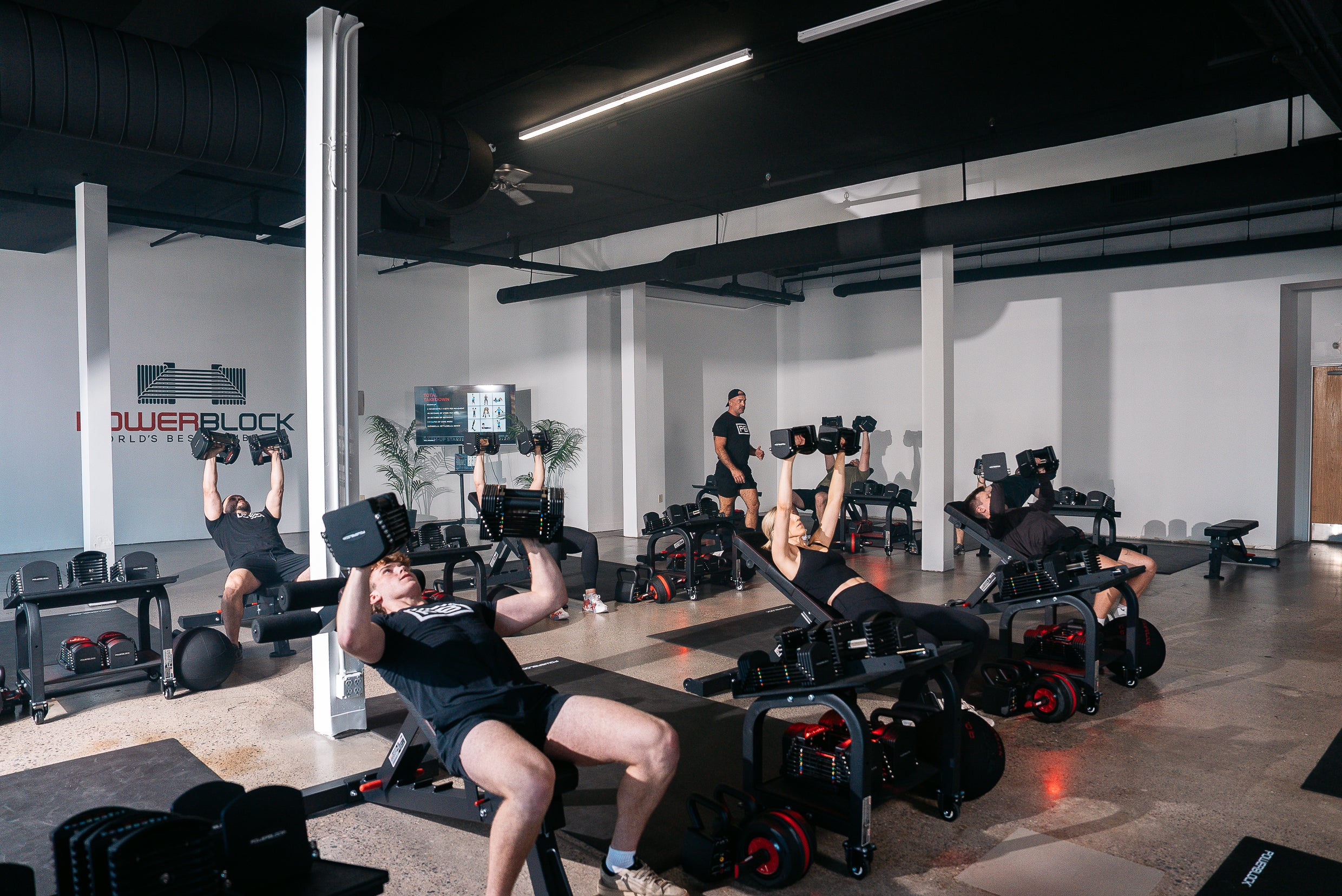 Powerblock fitness studio class, upper body day, members are seen doing dumbbell chest presses with powerblock adjustable dumbbells.